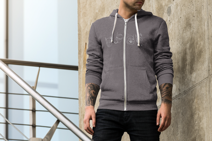 Man wearing a gray hoodie with a zipper, standing against a concrete wall.