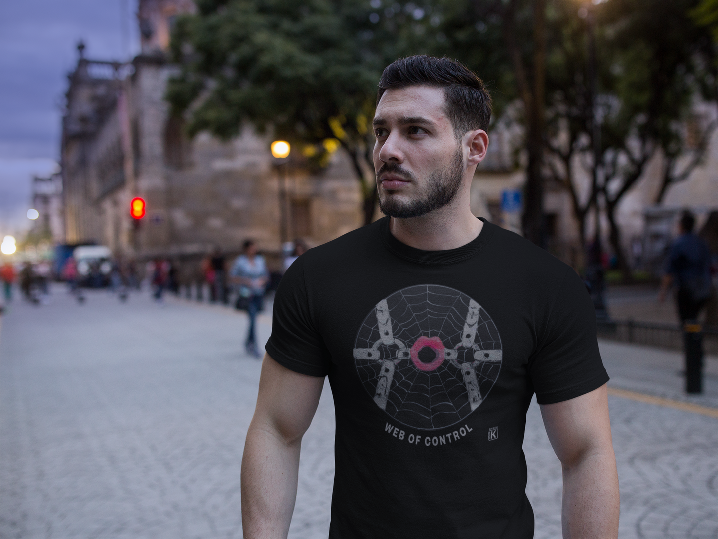 Man wearing a black t-shirt with a spider web design on a city street.