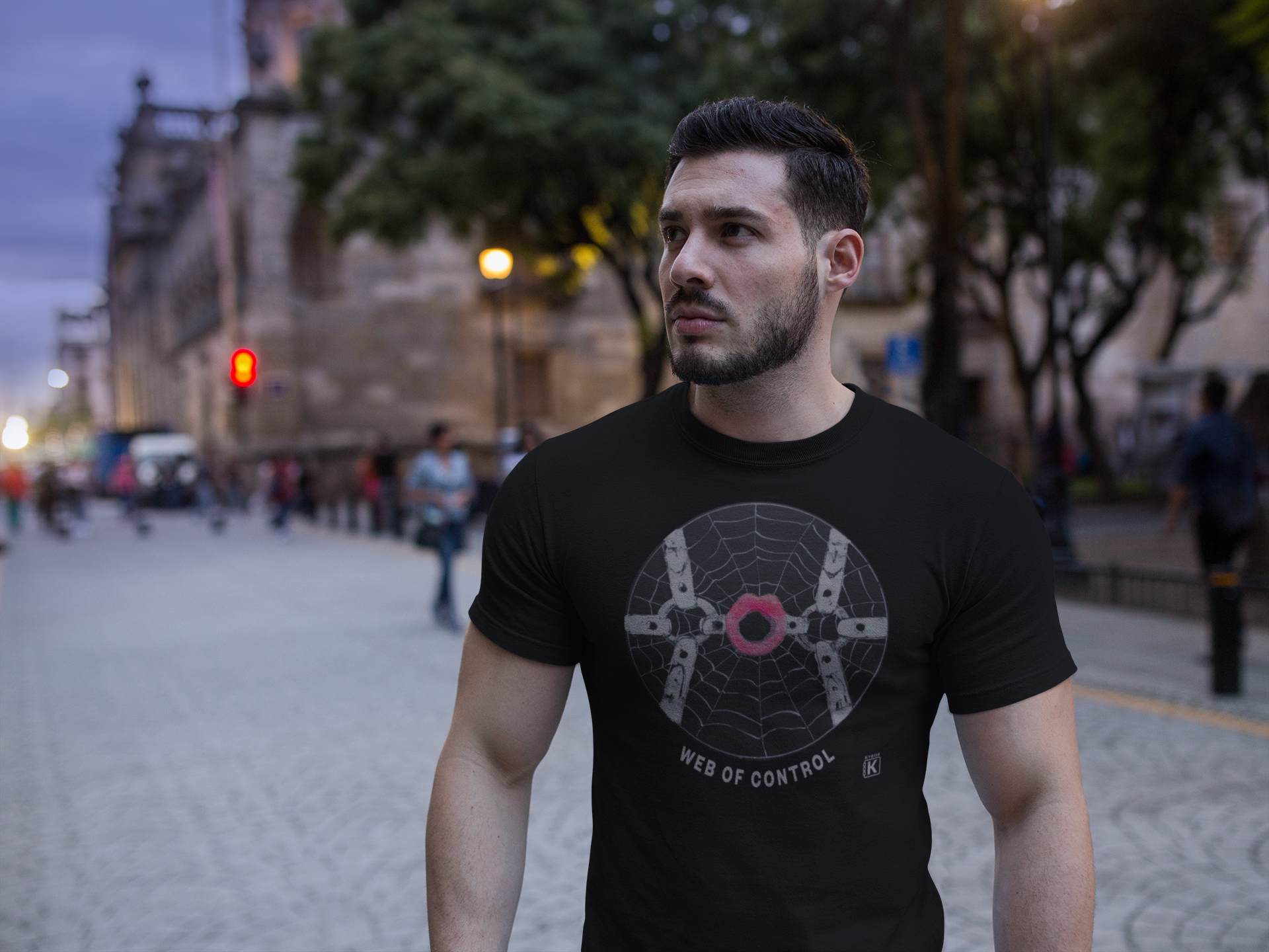 Man wearing a black t-shirt with a spider web design on a city street.