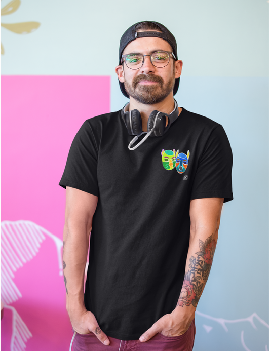 Man wearing a black t-shirt with colourful designs, standing against a light blue wall with abstract patterns.