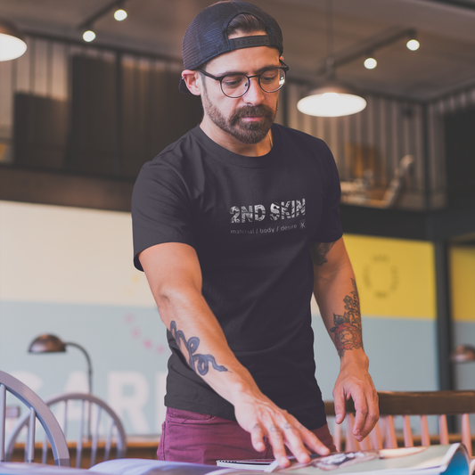 Man wearing a black t-shirt with '2ND SKIN' text in a casual setting.